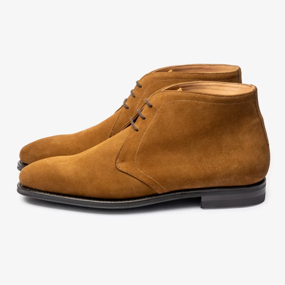 A pair of brown suede chukka boots with laces and a black sole.