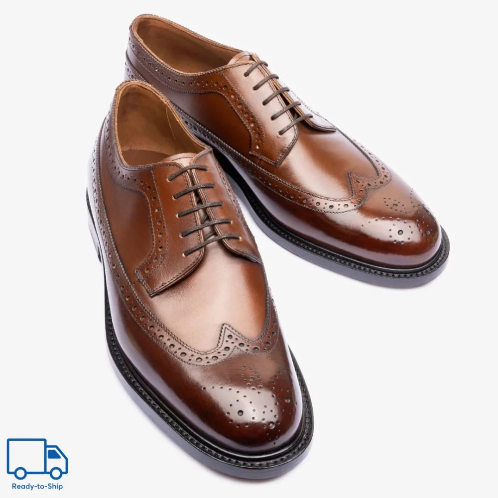 A pair of polished brown leather dress shoes with decorative brogue detailing and laces.