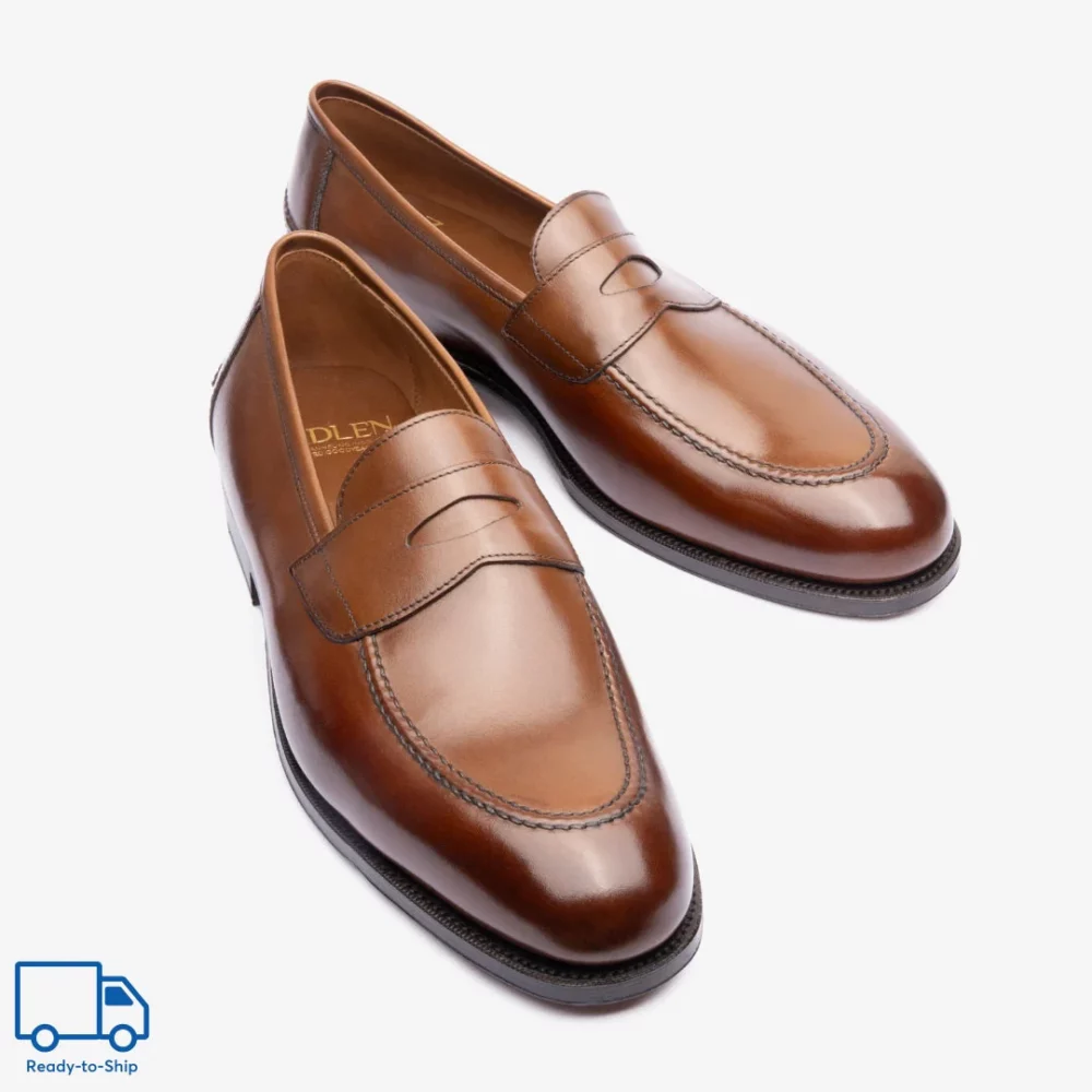 A pair of polished brown leather loafers with a decorative strap across the top.