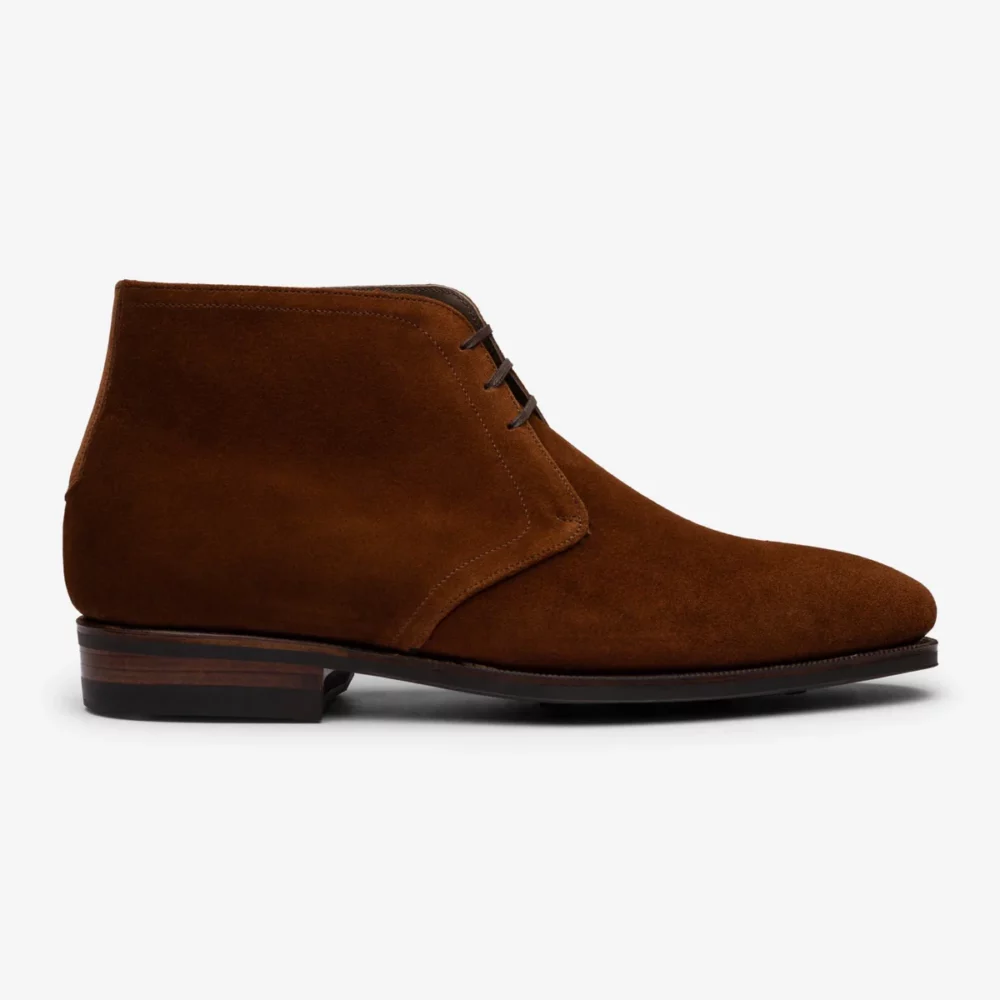 Brown suede ankle boots with a rounded toe and two lace eyelets.
