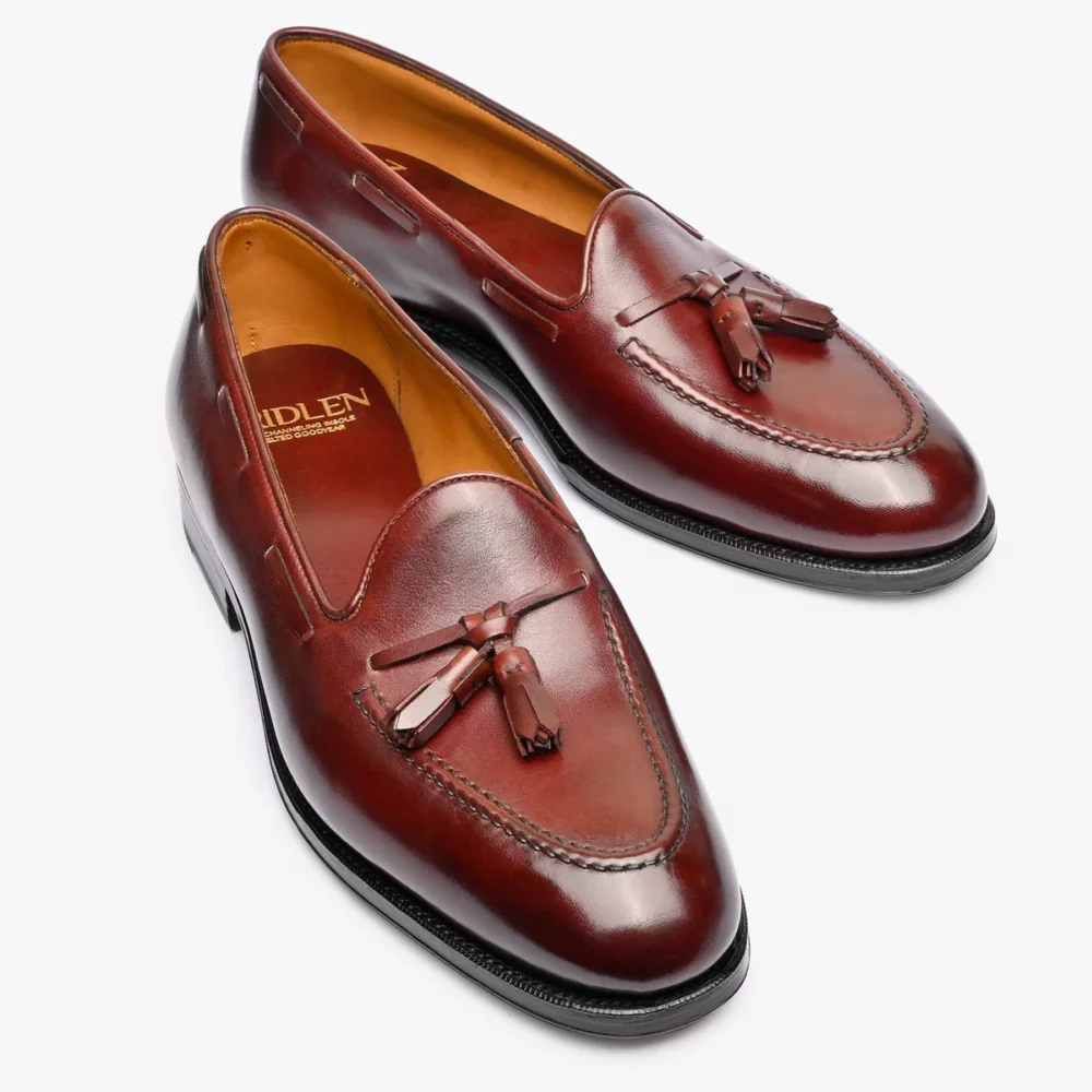 Brown leather loafers with tassels and a stitched design.