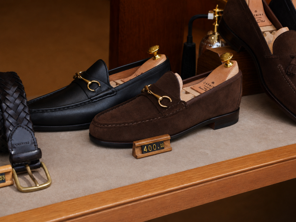 A pair of brown and black loafers with gold accents displayed on a shelf, priced at $400.