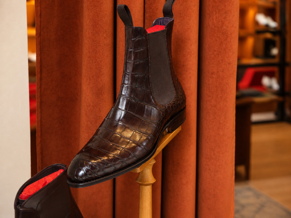 A dark brown crocodile leather Chelsea boot with a red interior.