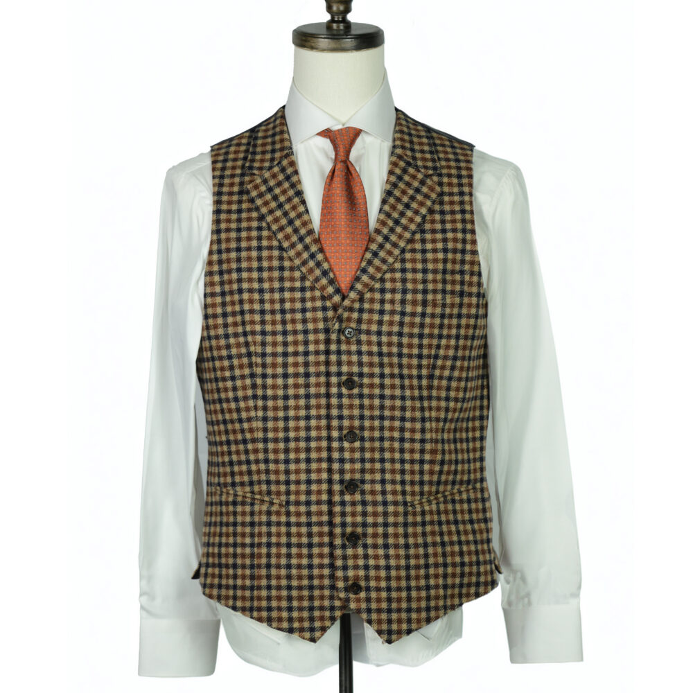 A tailored brown and orange plaid vest with a white shirt and an orange tie displayed on a mannequin.