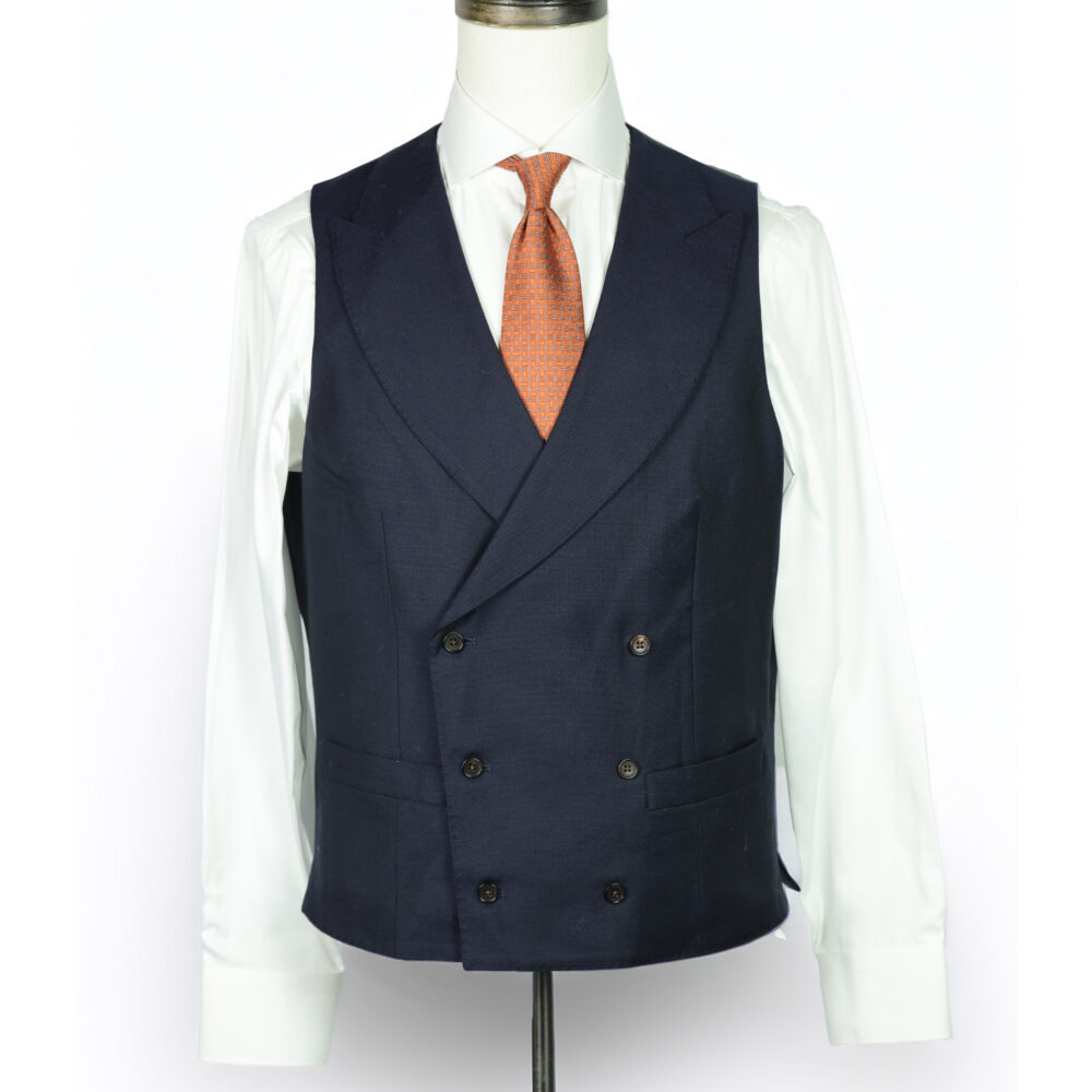 A navy double-breasted vest with a white dress shirt and an orange tie.