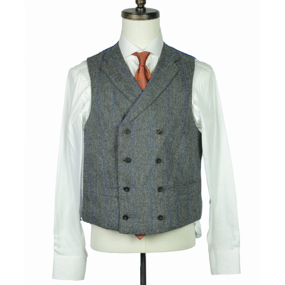A gray tweed vest with blue pinstripes, paired with a white shirt and orange tie, displayed on a mannequin.