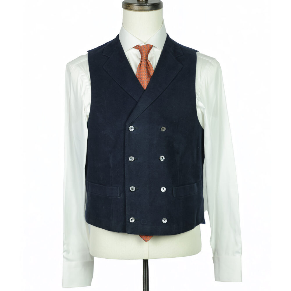 A tailored navy vest with a double-breasted design and silver buttons, worn over a white shirt and orange tie.