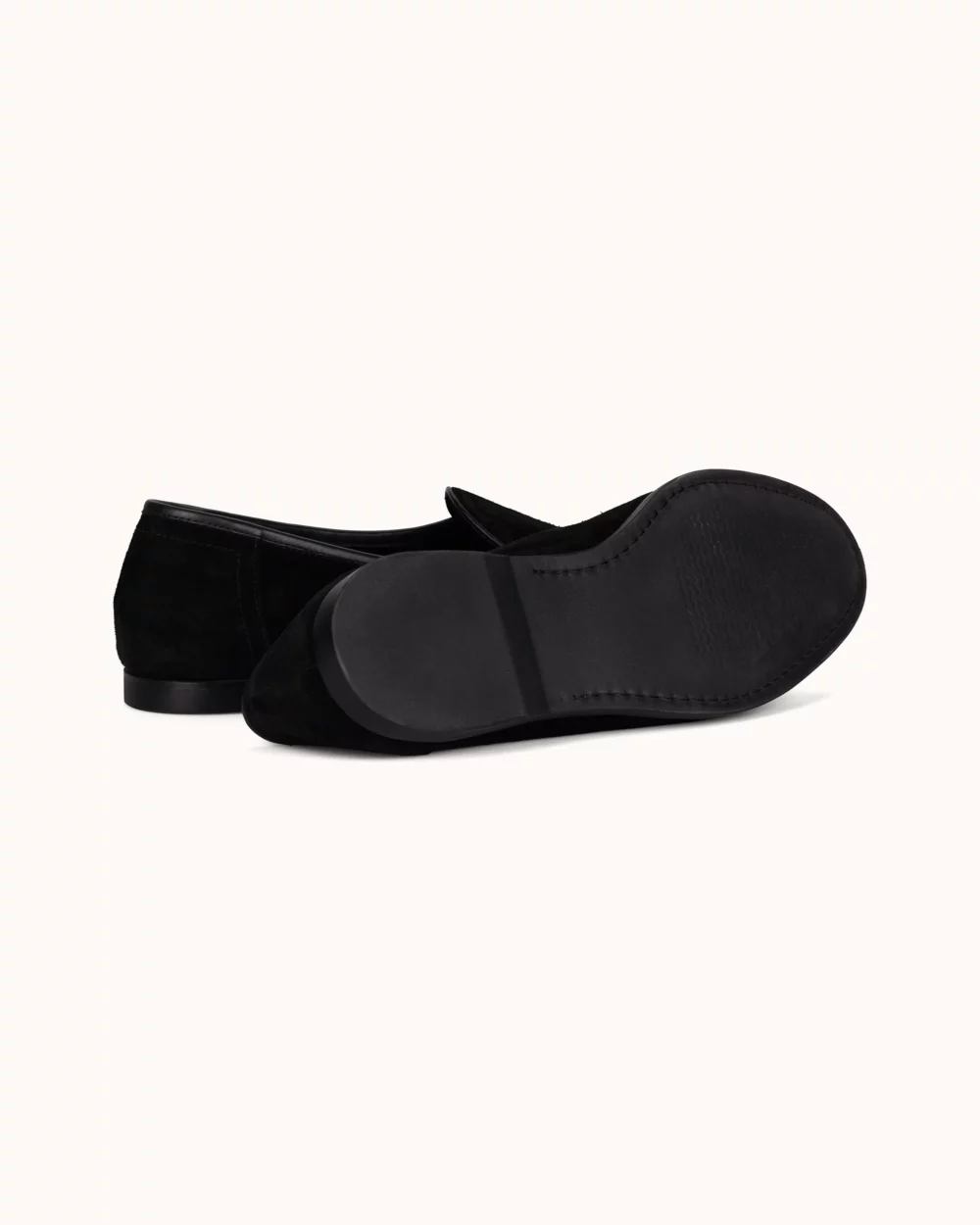 Black suede flats with a low heel, showing the soles and side view.