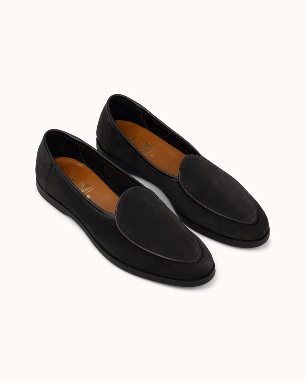 A pair of black suede loafers with a smooth finish and a pointed toe design.