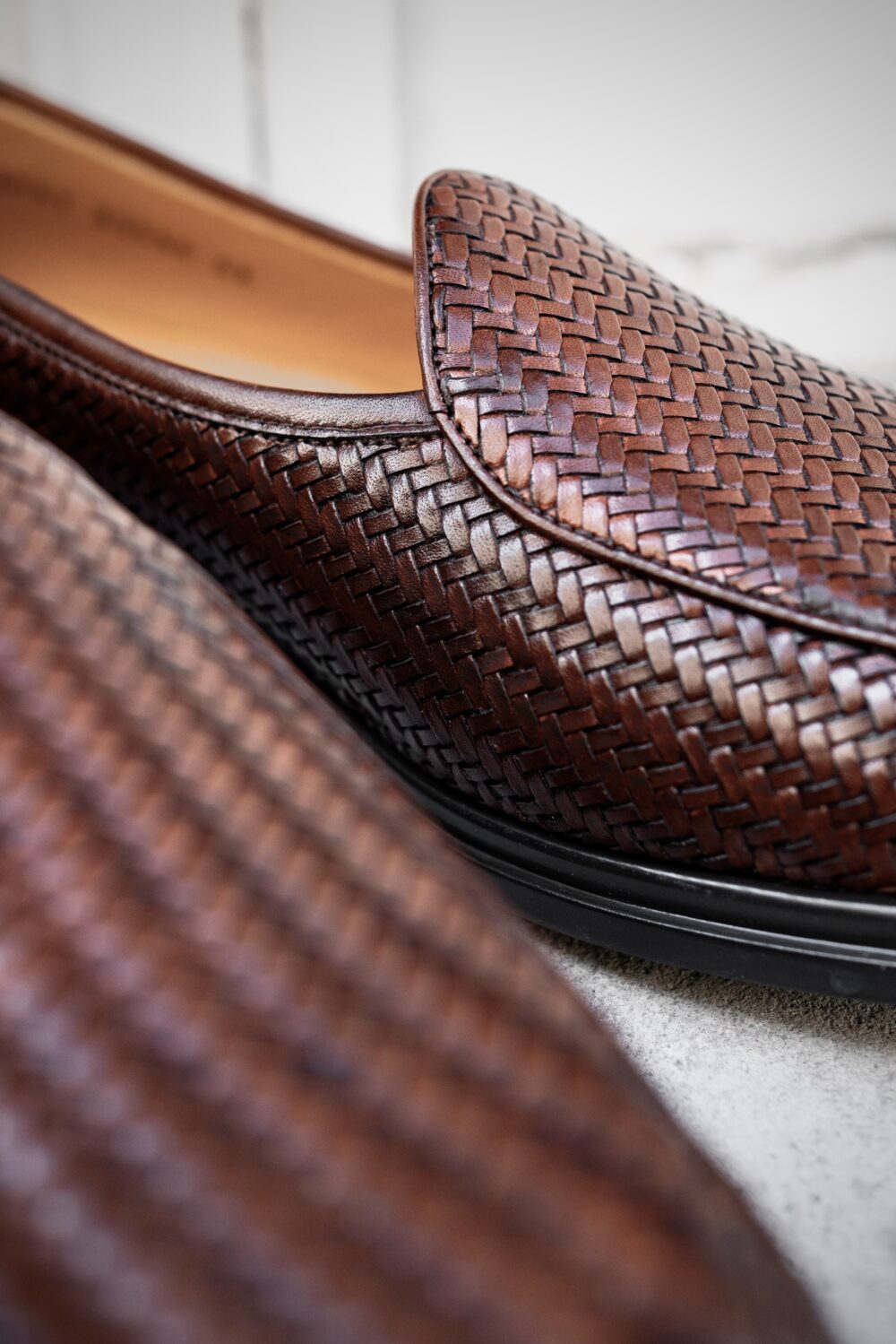 A close-up of brown woven leather slip-on shoes.
