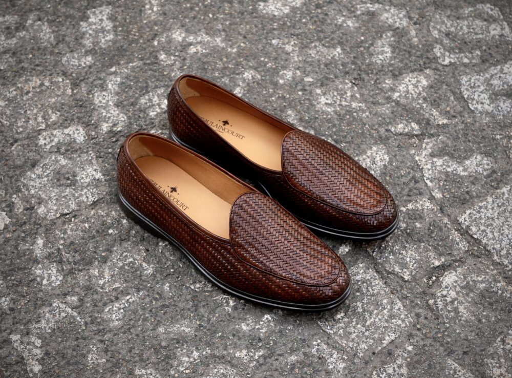 A pair of brown woven leather loafers with a smooth interior.