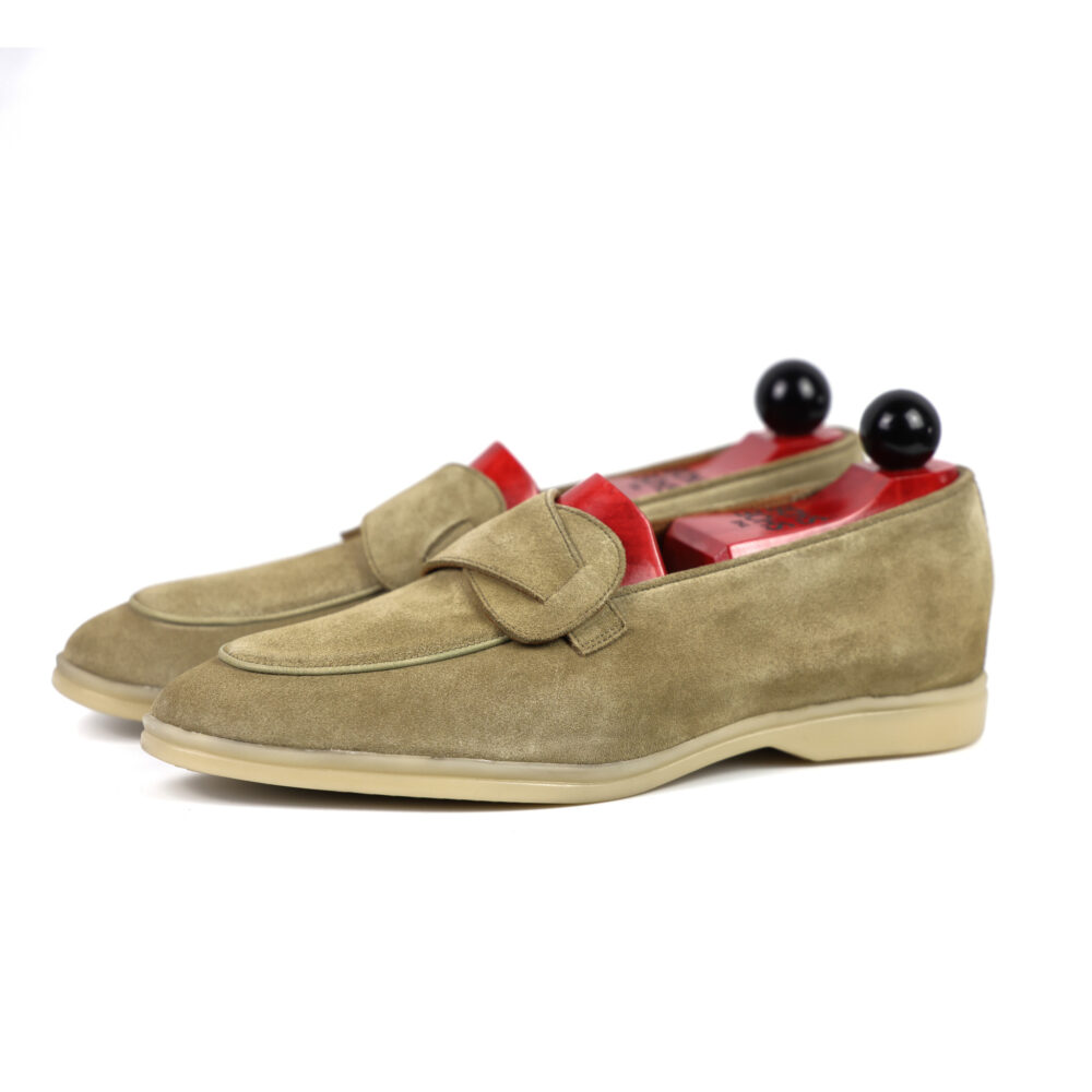 A pair of olive green suede loafers with red insoles and black shoe trees.