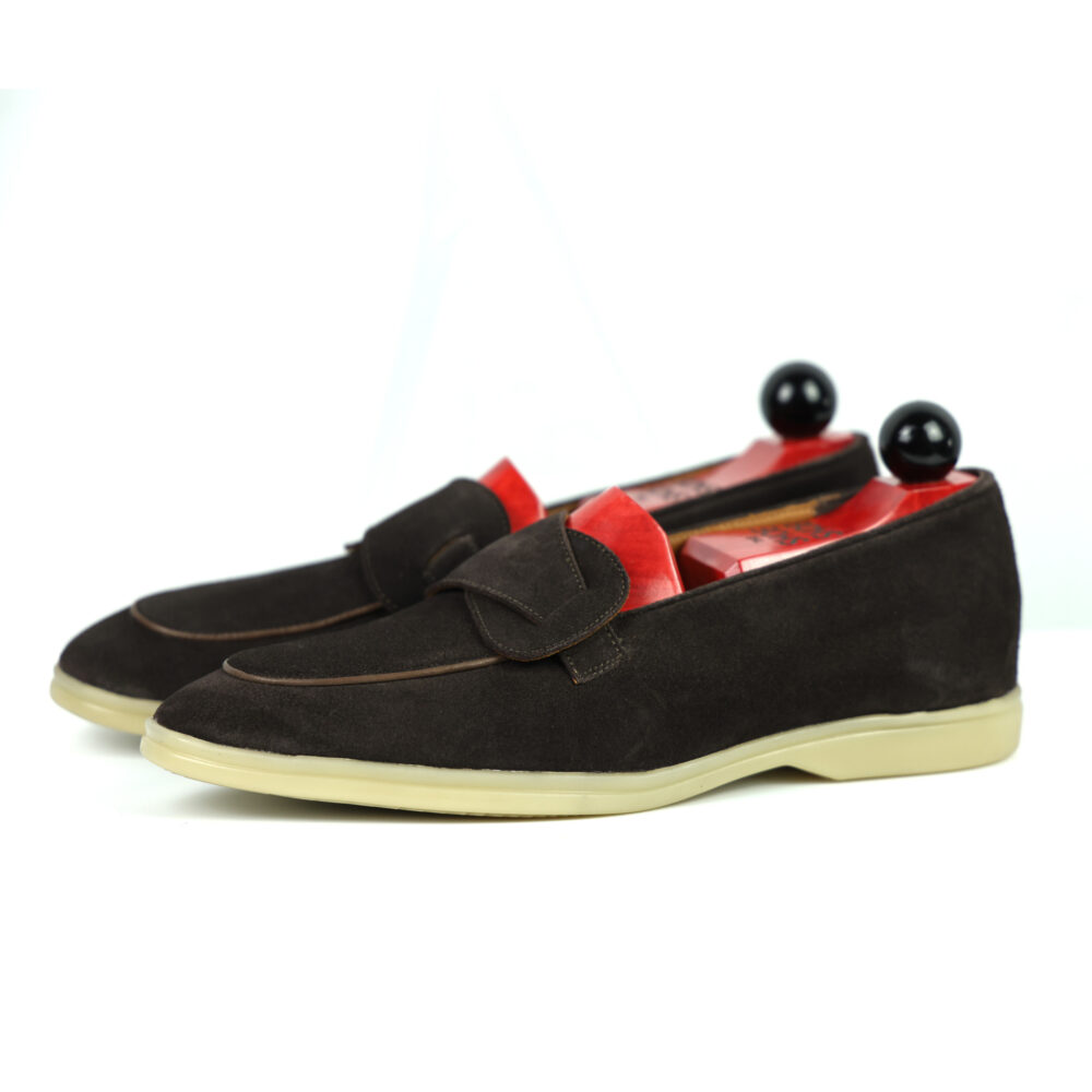 A pair of dark brown suede loafers with red insoles and black shoe trees.