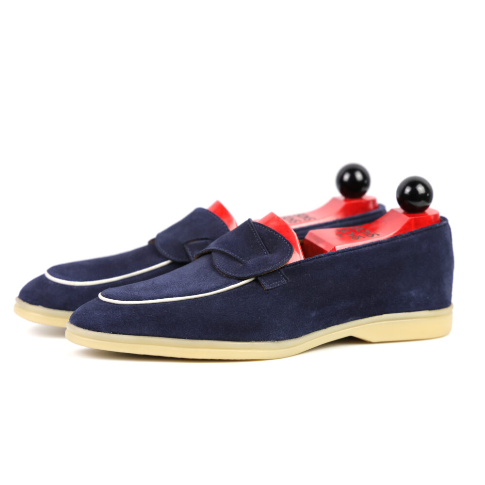 Navy blue suede loafers with a red interior and black decorative knobs on the heels.
