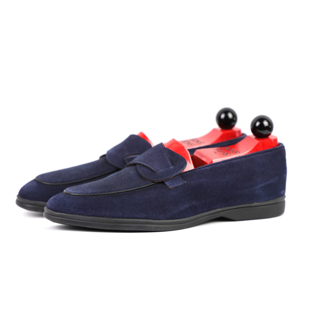 Navy blue suede loafers with red insoles and black shoe trees.