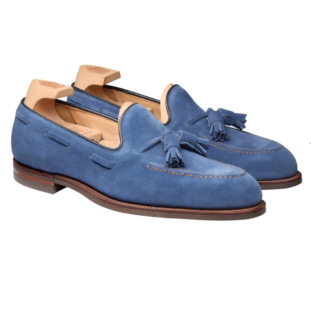 A pair of blue suede loafers with tassels and a brown leather sole.
