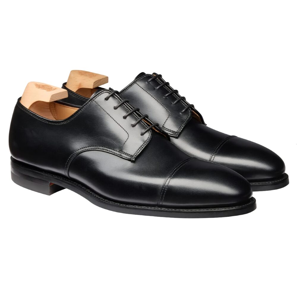 A pair of black leather dress shoes with wooden shoe trees inserted.