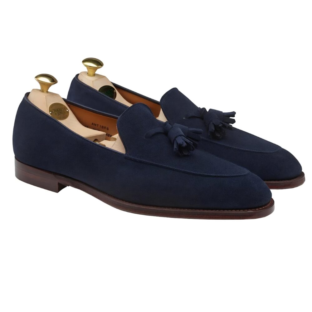 Navy blue suede loafers with tassels and wooden shoe trees.
