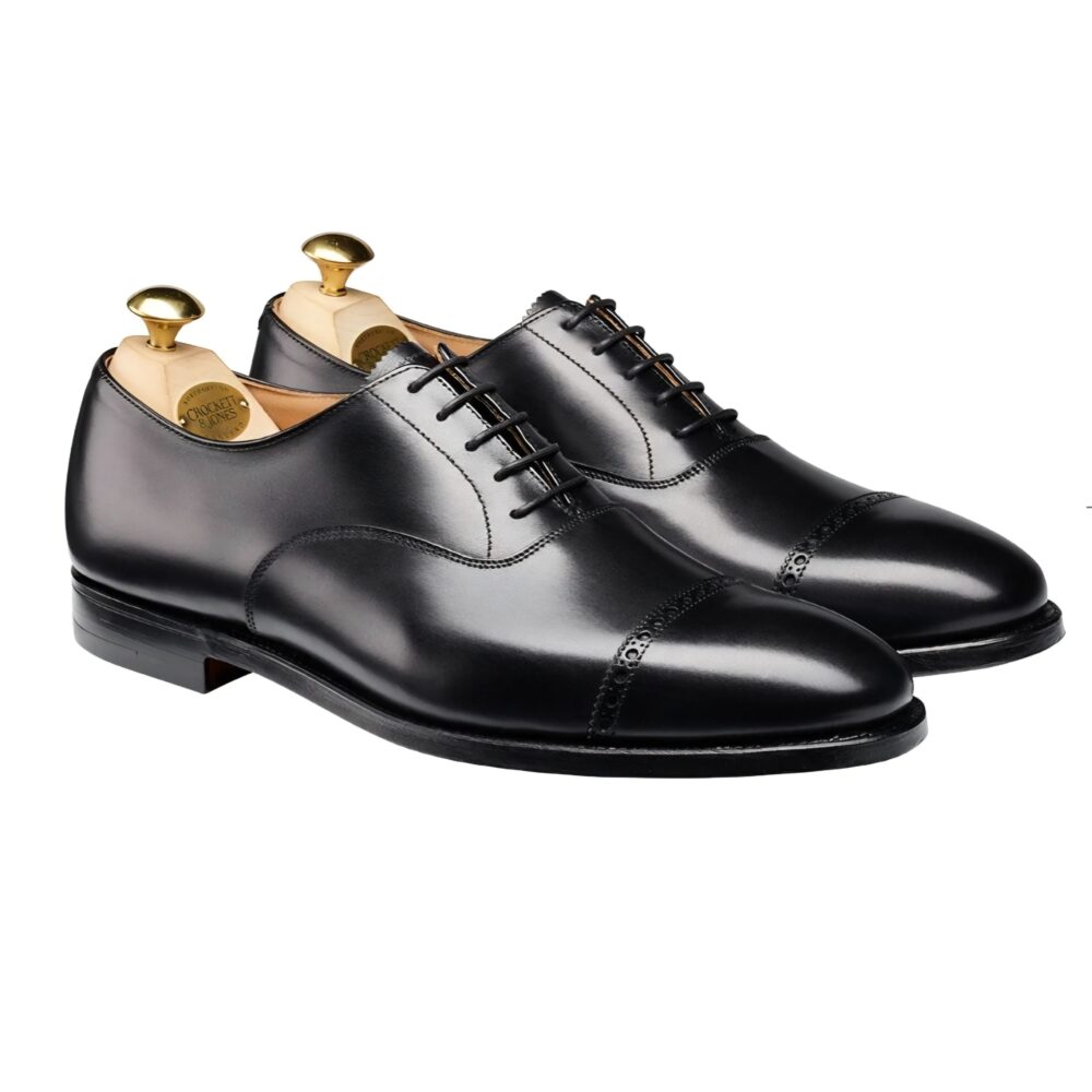 A pair of polished black leather dress shoes with decorative stitching and wooden shoe trees.
