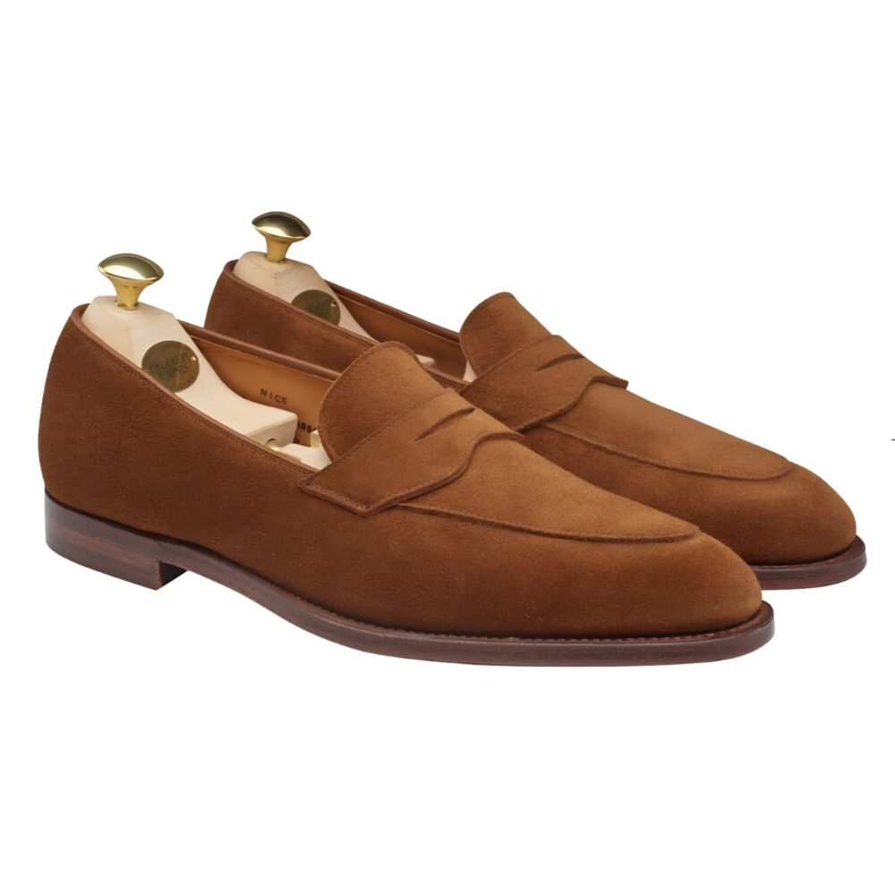 Brown suede loafers with a stitched detail and wooden shoe trees inside.