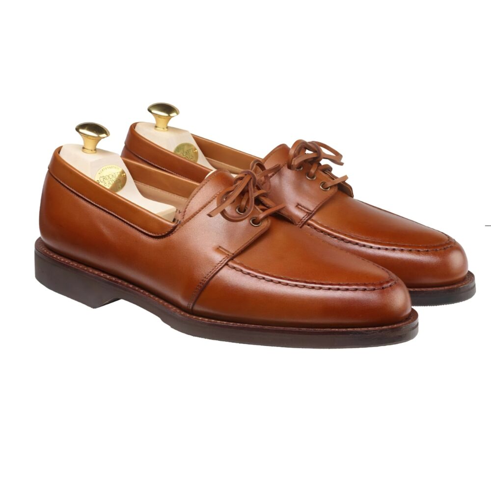 A pair of brown leather shoes with laces and shoe trees inside.