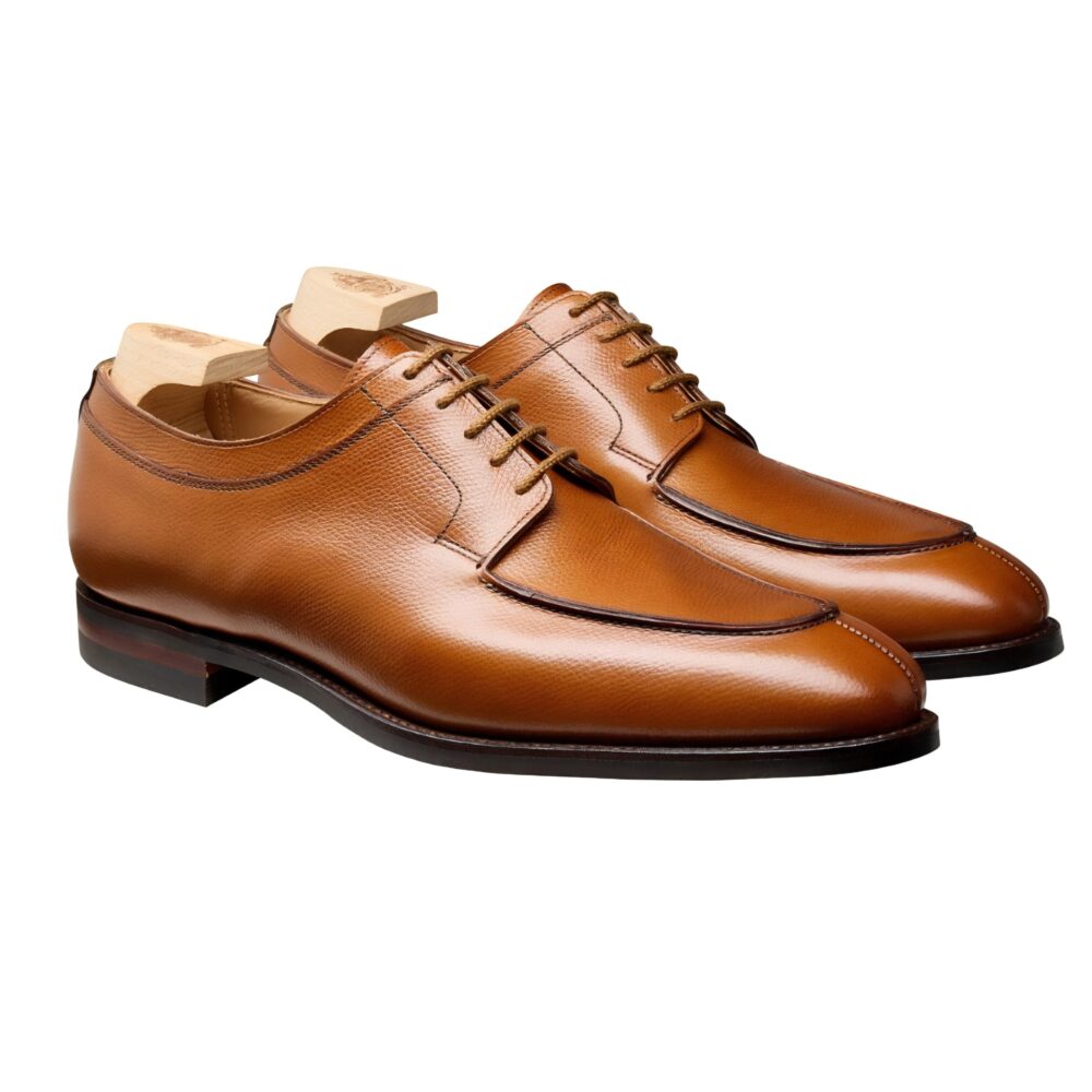 A pair of polished brown leather dress shoes with lace-up detailing and wooden shoe trees.