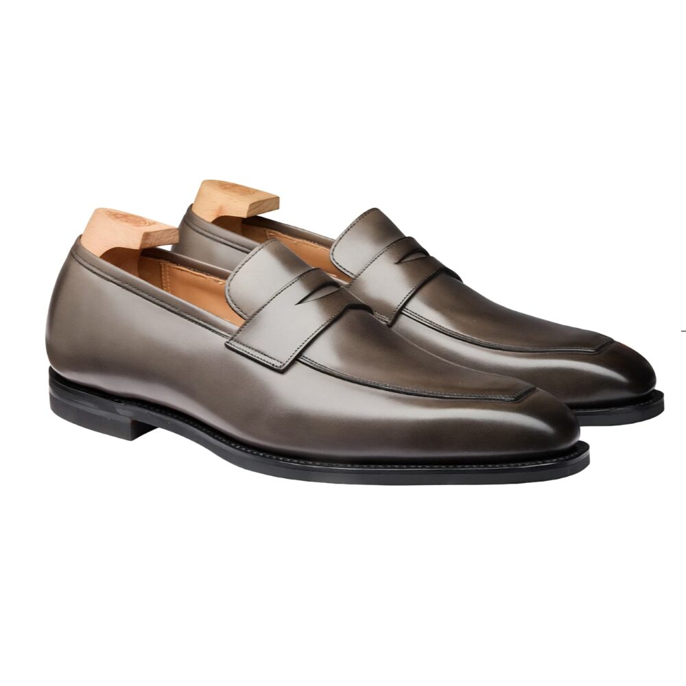 A pair of dark brown leather loafers with a decorative strap and wooden shoe trees inside.