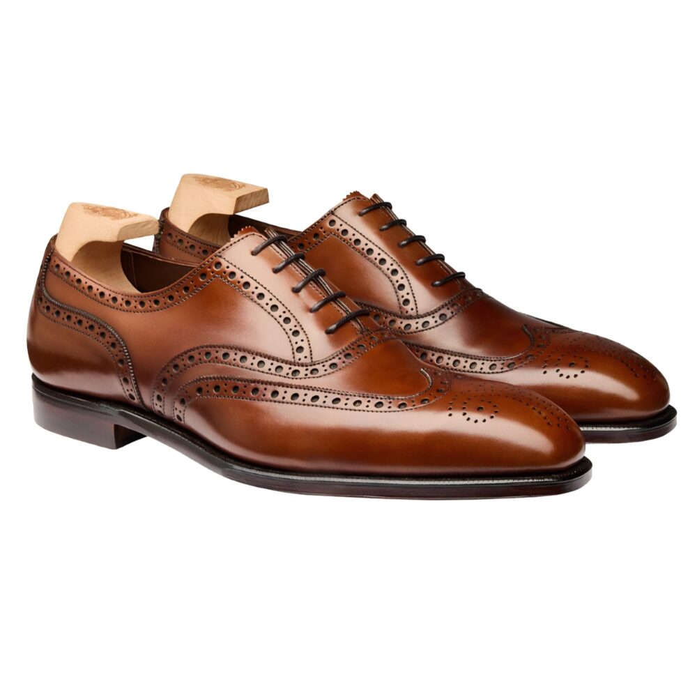 A pair of polished brown leather dress shoes with decorative brogue detailing.