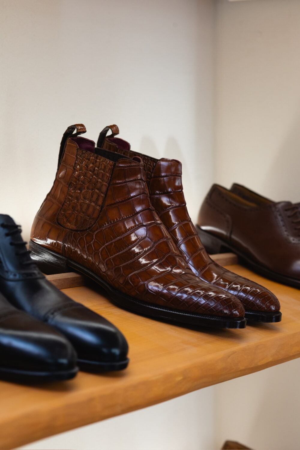 Brown crocodile leather ankle boots with a glossy finish.