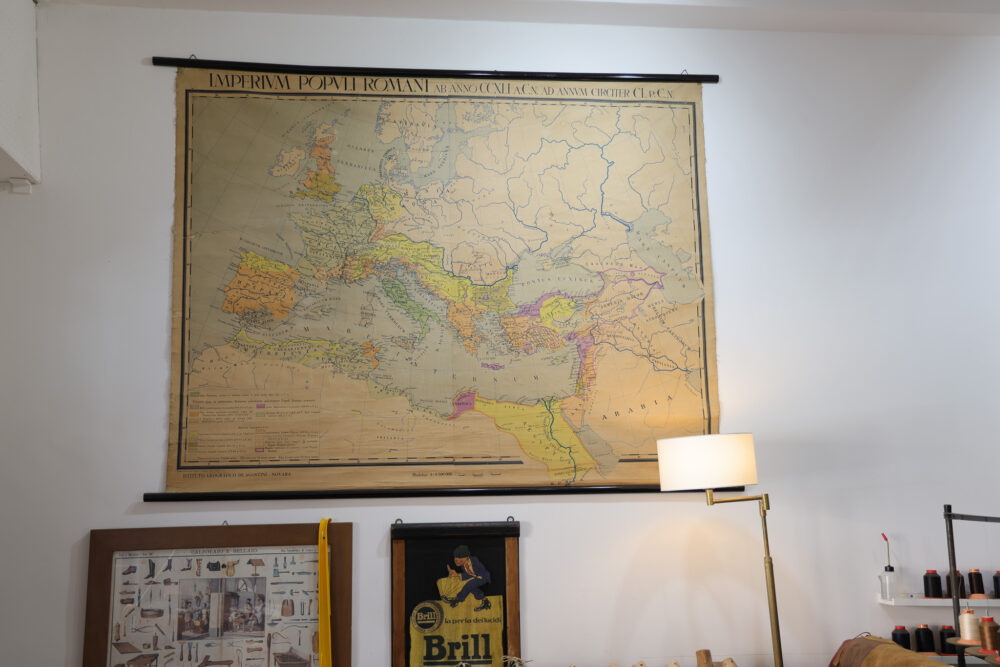 A vintage map of the Roman Empire, featuring various colors to indicate different regions, hangs on the wall.