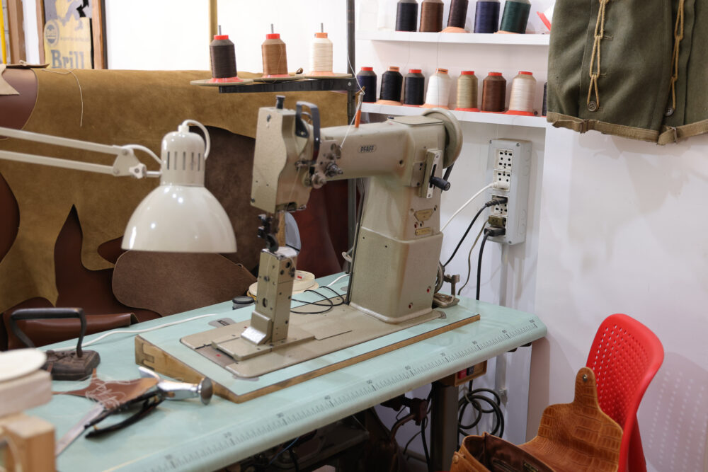 A vintage sewing machine with a white lamp and spools of thread in various colors on a table.