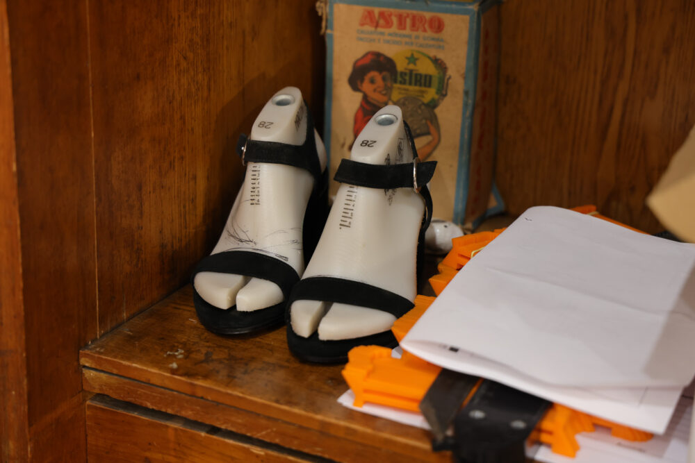 A pair of black and white open-toed shoes displayed on a wooden surface.