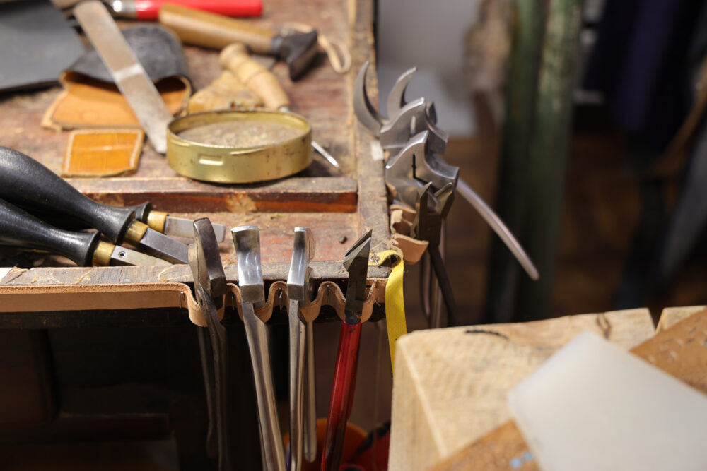 A collection of shoemaking tools, including metal lasts and wooden handles, arranged on a workbench.