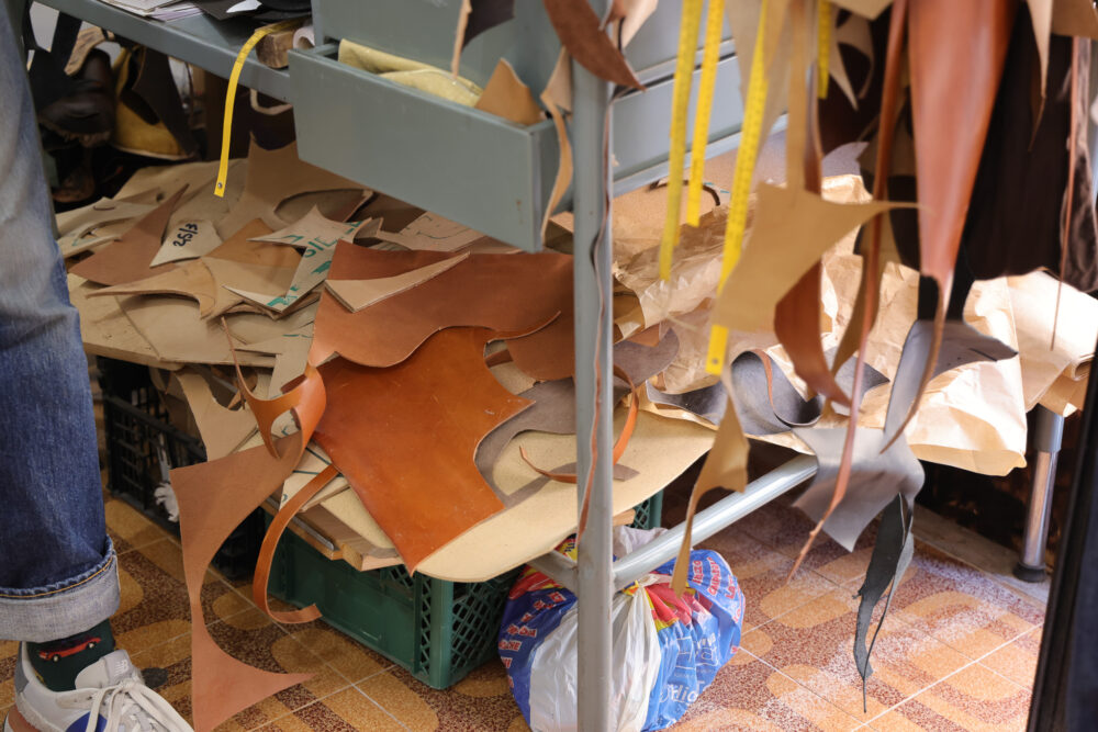 A collection of leather scraps in various shades, including brown and tan, scattered on a worktable.