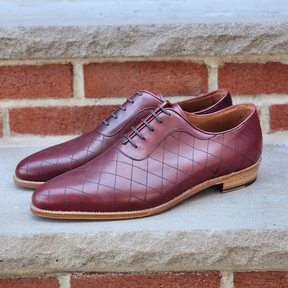 Maroon leather dress shoes with a quilted pattern and brown soles.