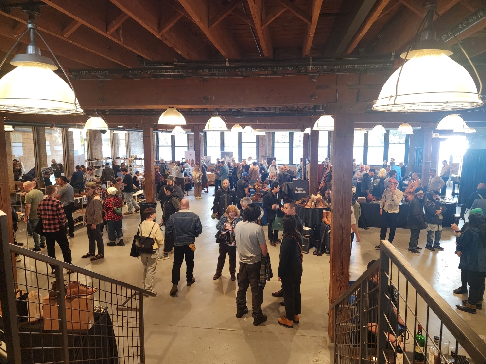 A bustling indoor event featuring many attendees interacting and browsing various booths.