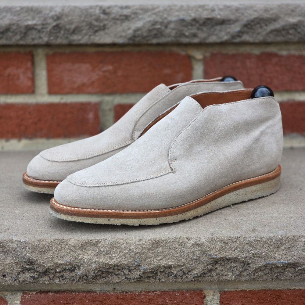 Beige suede slip-on shoes with a brown leather sole.