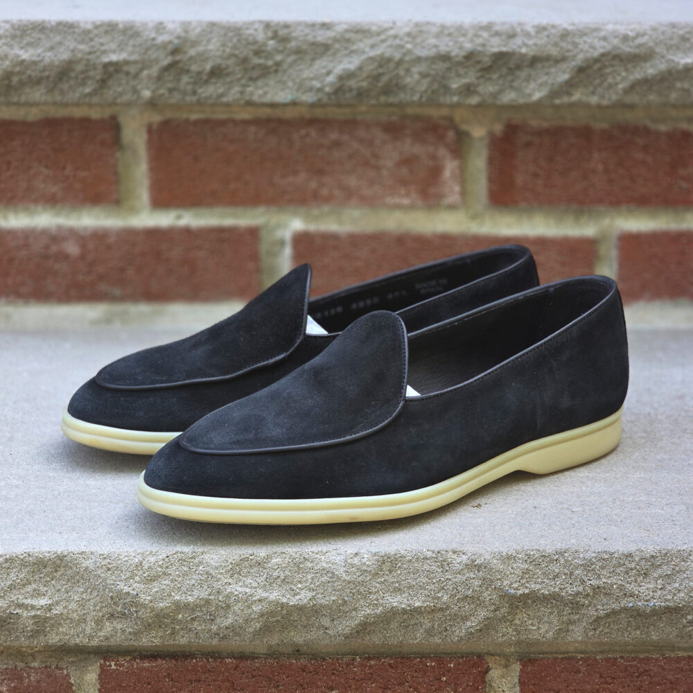A pair of black suede loafers with a cream-colored sole.