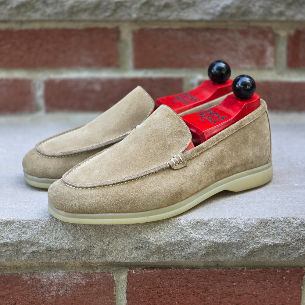 Tan suede loafers with red insoles and black shoe trees.