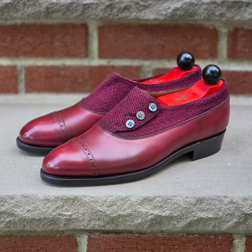 Burgundy leather shoes with a textured upper and decorative buttons.