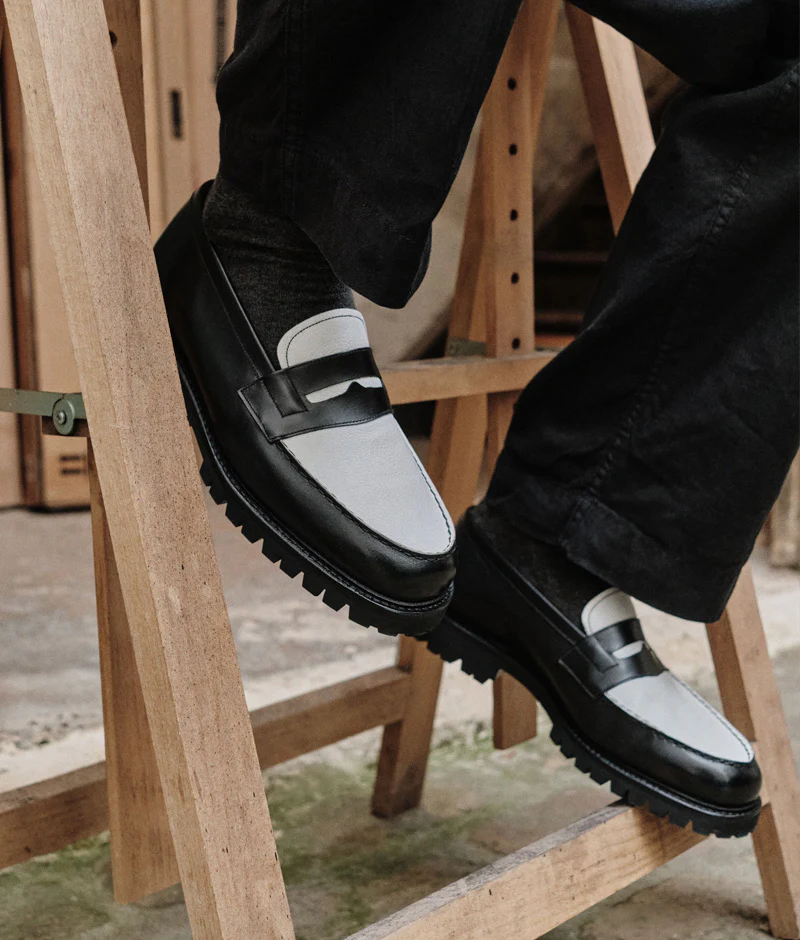A close-up of stylish black and gray loafers worn with dark pants, featured in the Septieme Largeur Summer Sale 2026.