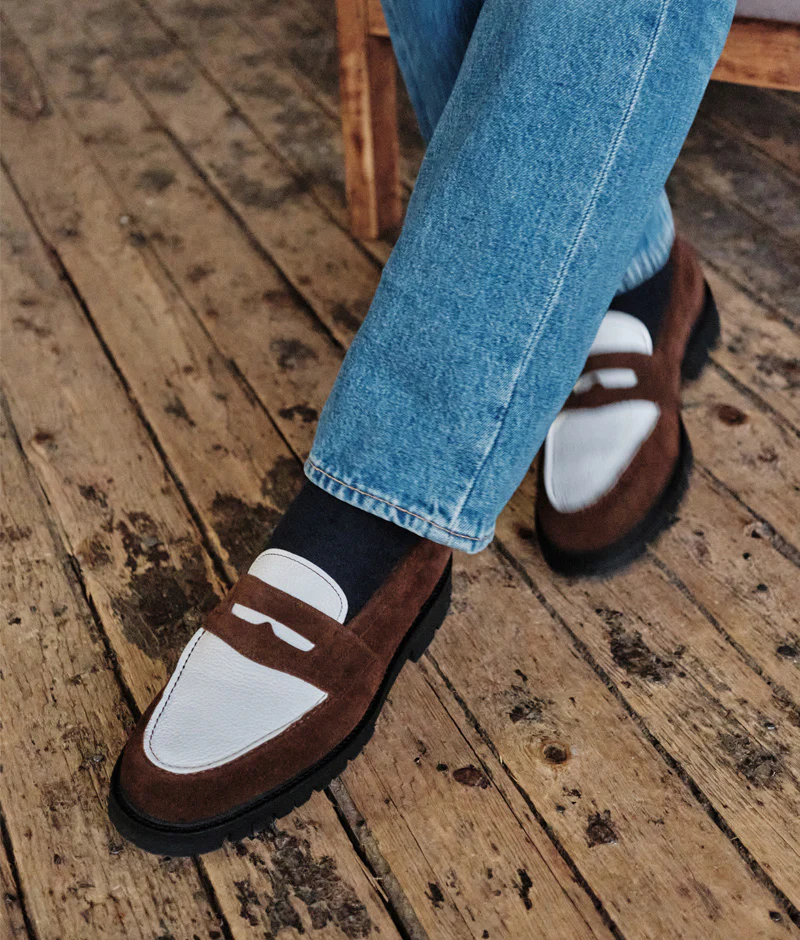 A close-up of brown and white loafers worn with blue jeans, featured in the Septieme Largeur Summer Sale 2026.