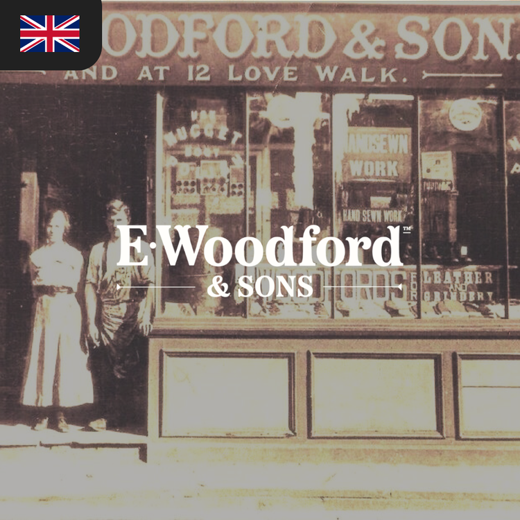 A vintage photograph features a man and woman standing in front of a shop window displaying the sign "E. Woodford & Sons."
