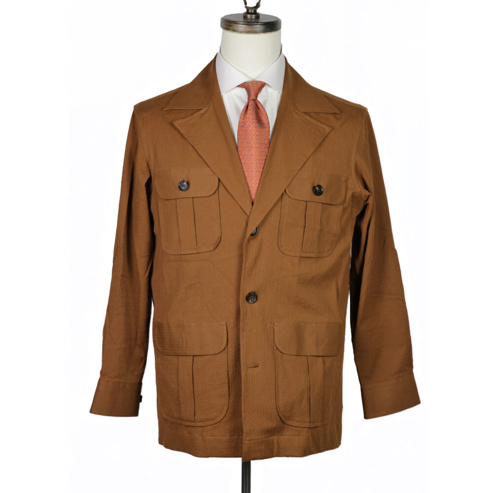 A brown, textured jacket with two front pockets displayed on a mannequin, paired with a white shirt and orange tie.