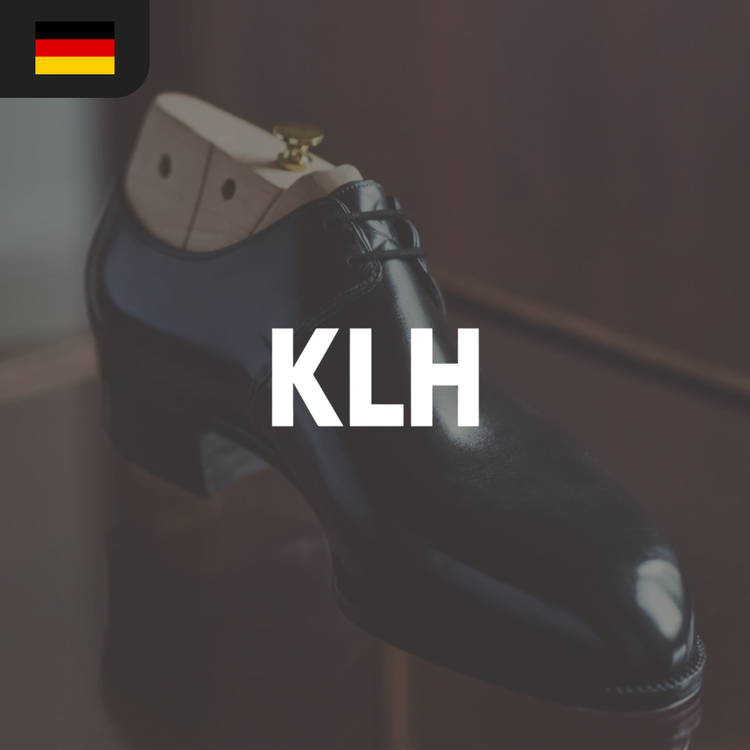 A polished black dress shoe with a wooden shoe tree inserted.