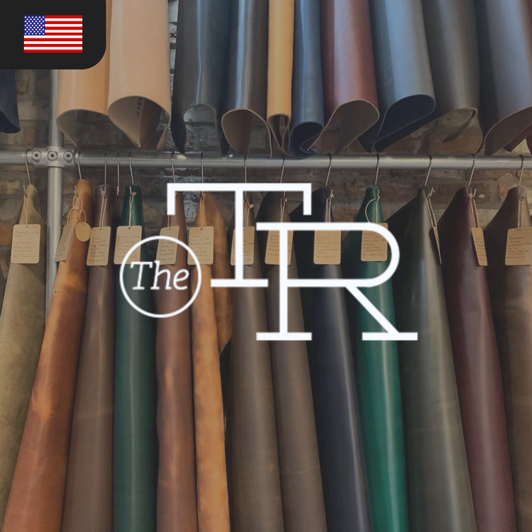 A collection of leather hides in various colors, including brown, green, and black, with tags hanging from each piece.