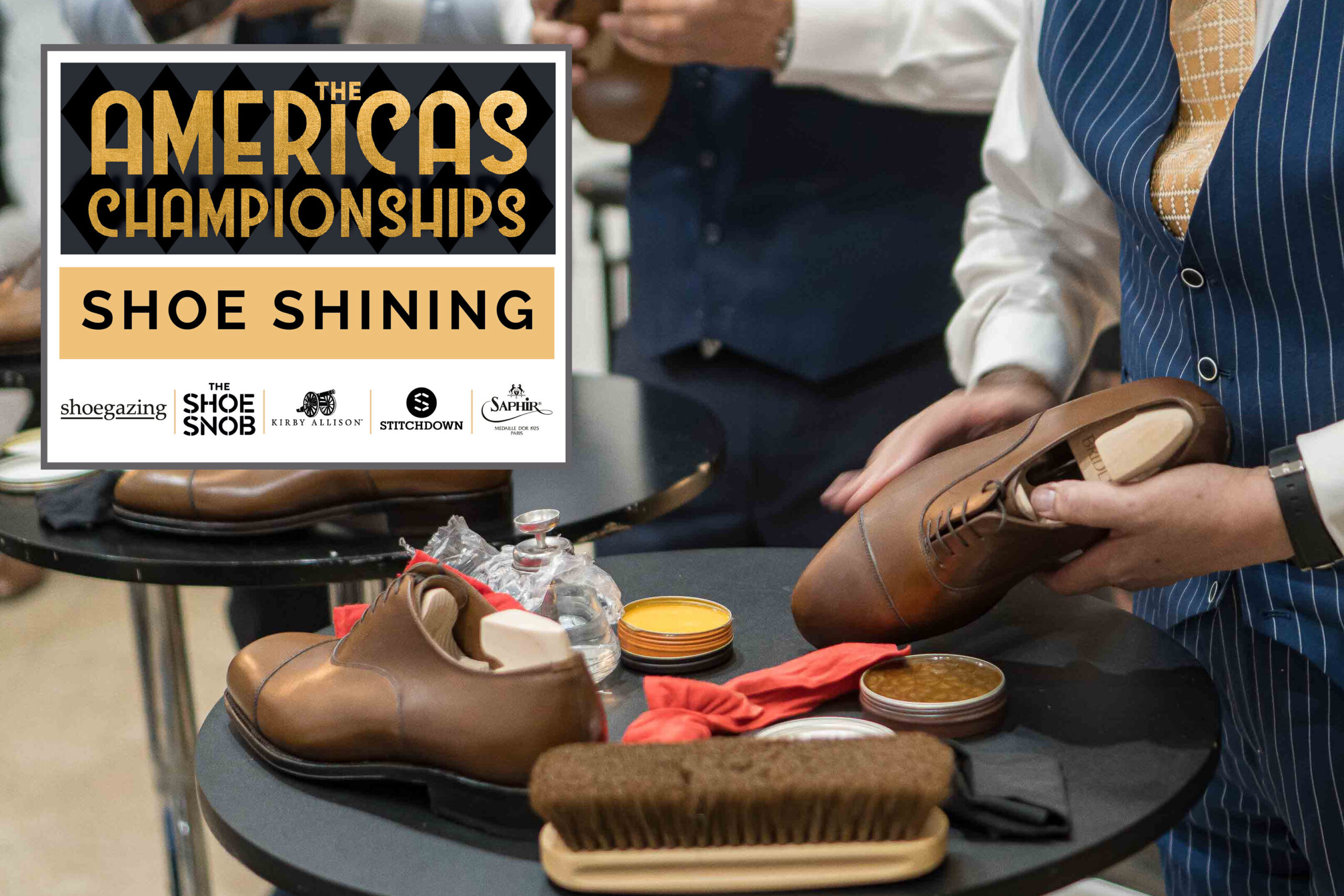 A person holds a polished brown leather shoe while surrounded by shoe shining supplies, including brushes and polish containers.