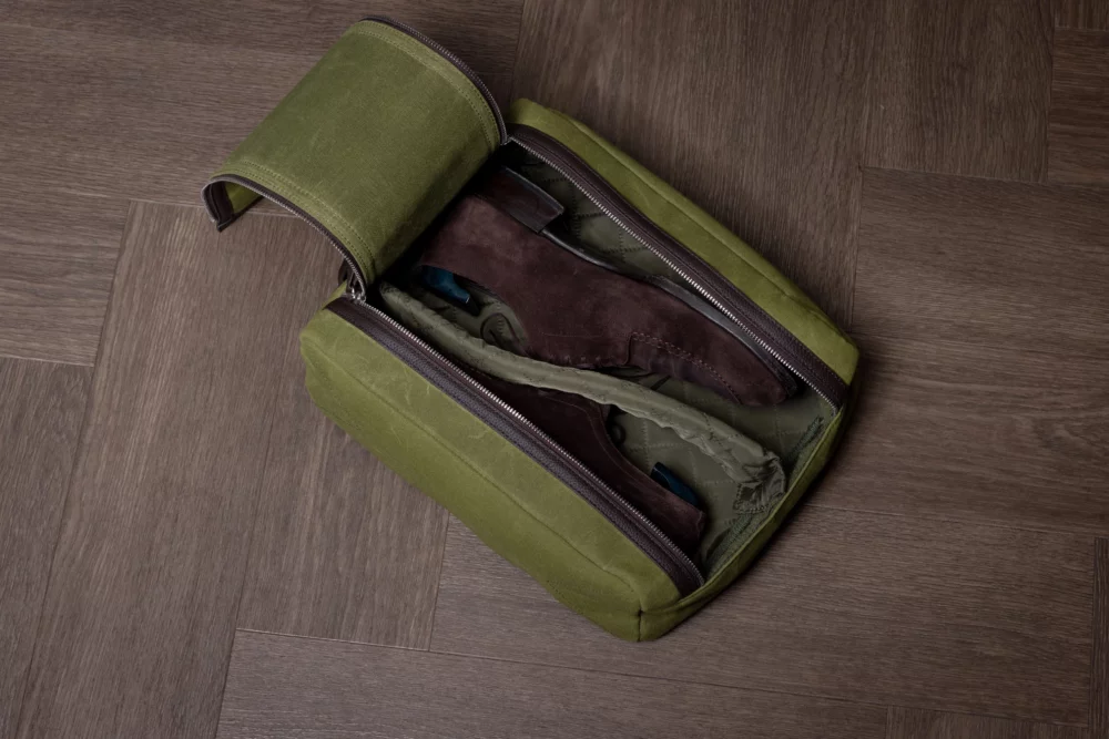 The Arterton Signature Shoe Bag is an olive green travel bag containing a pair of brown suede shoes.