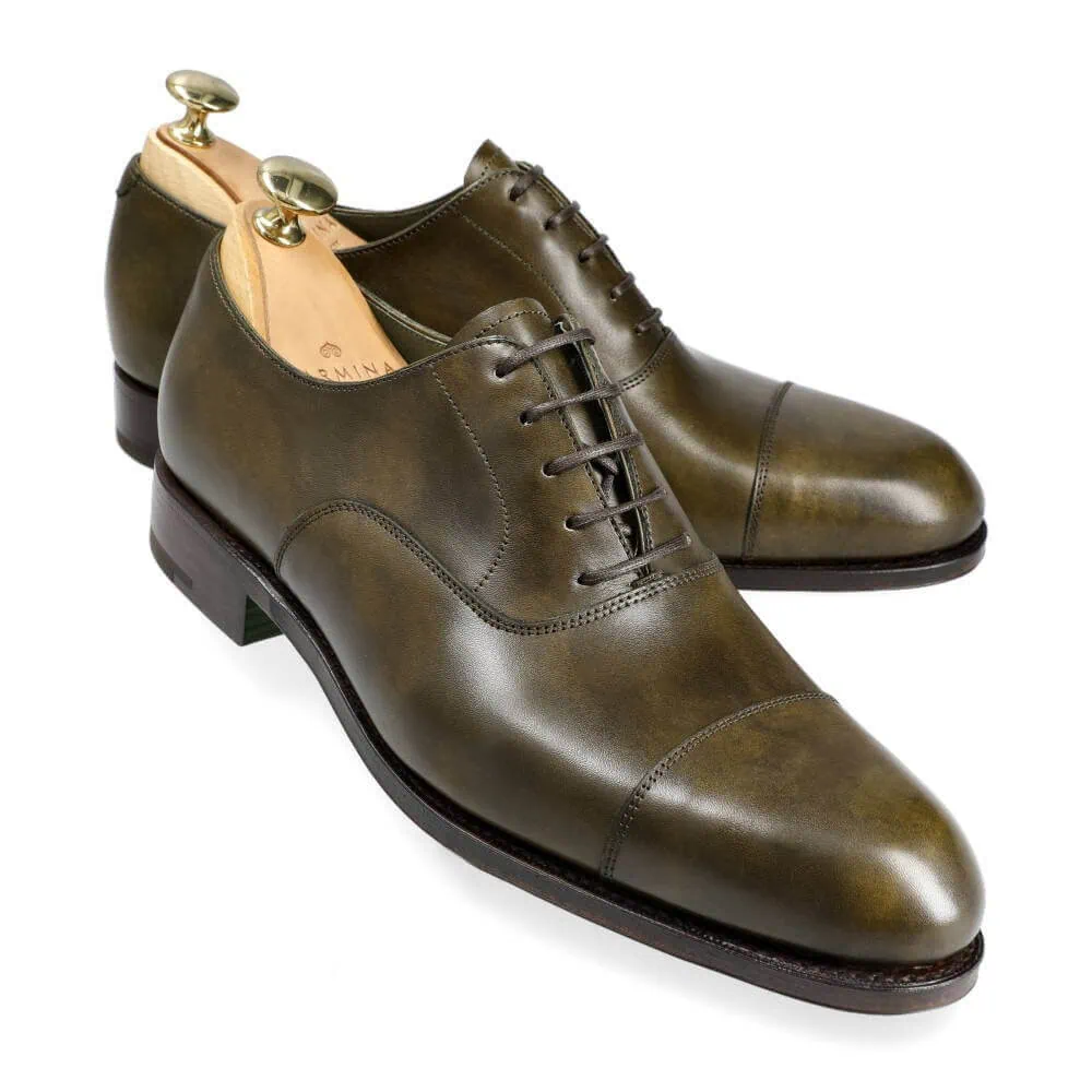 Olive green leather dress shoes with laces and gold shoe trees.