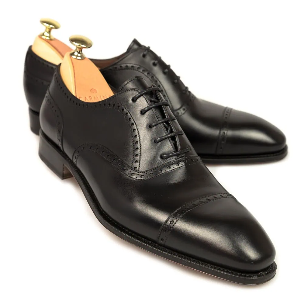 Black leather dress shoes with a cap toe and decorative broguing.